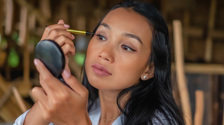 woman doing her eye makeup