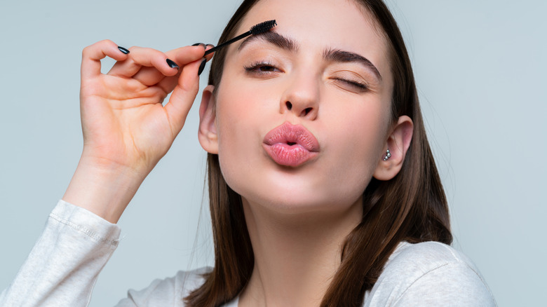 Woman brushes brow with spoolie