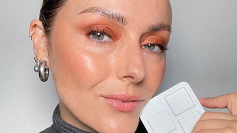model holding eyeshadow palette with warm copper monochromatic eye