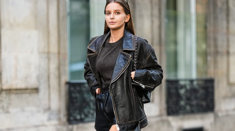 woman wearing leather jacket, leather shorts, sweater, and knee high boots