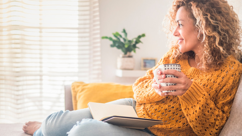 woman reading book holding a cup