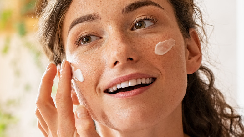 woman applying moisturizer on face