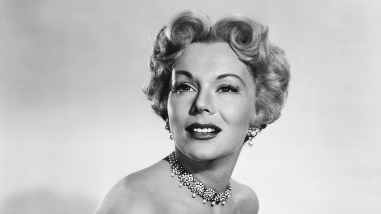 Eva Gabor posing in a black and white photo wearing a crystal choker and earrings.