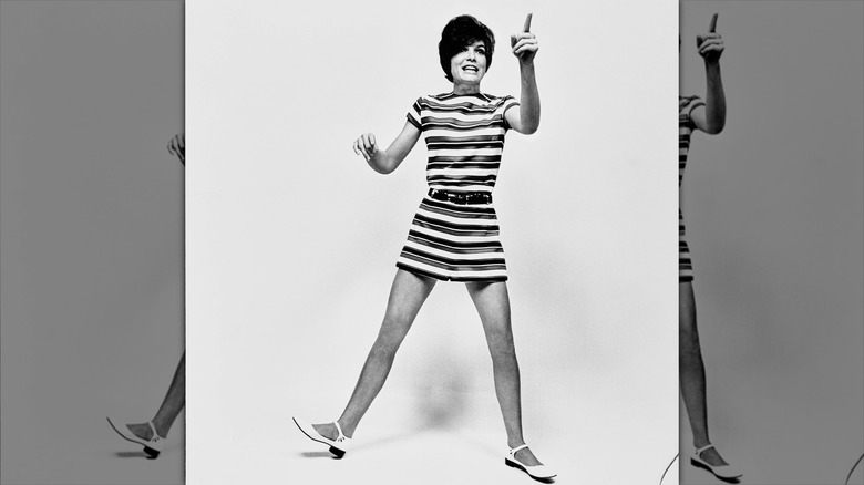Katharine Ross poses wearing a striped mini dress and a pixie cut.