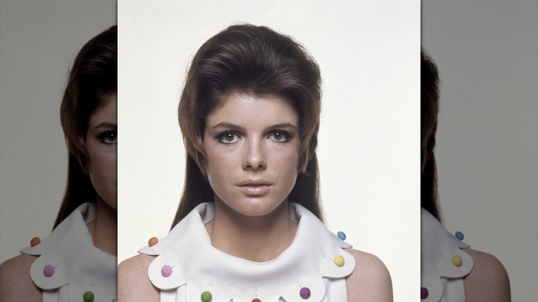 Katharine Ross poses wearing a floral-inspired collar with colorful buttons.