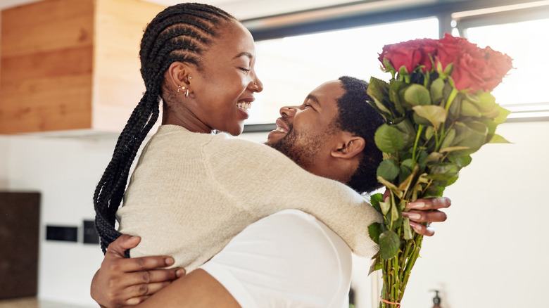 hugging couple holding red roses