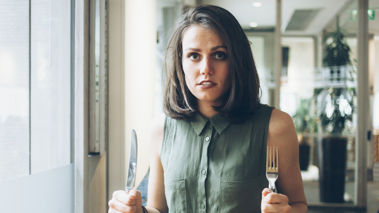 Hungry woman holding cutlery 