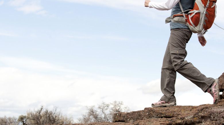 A woman walking along a rocky path while out on a day hike.