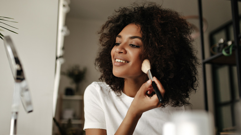 woman applying makeup with brush