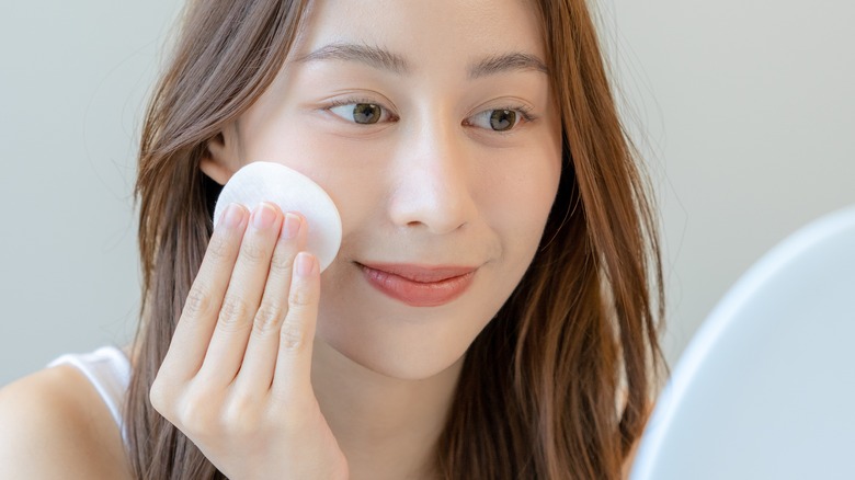 Woman using cotton pad on face