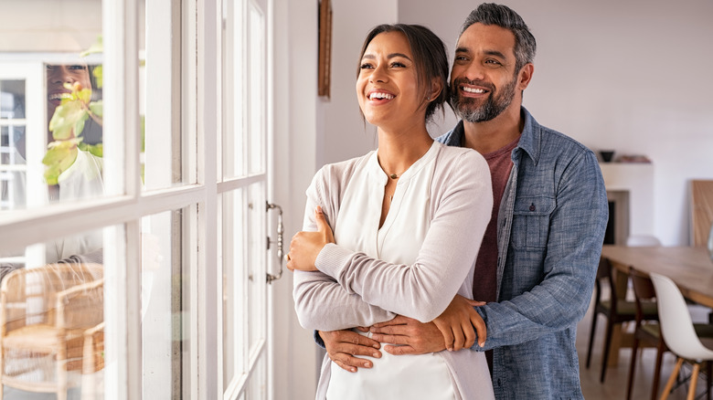 Happy couple looks out window together