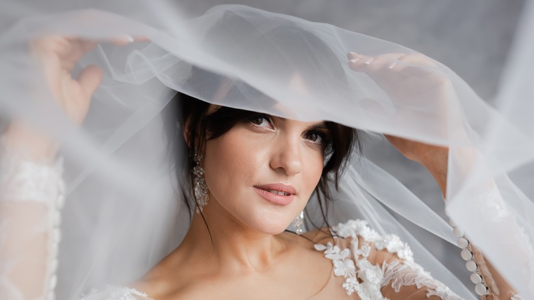 Brunette bride lifting wedding veil