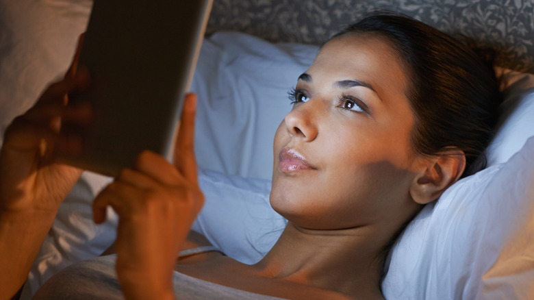 Woman reading tablet in bed