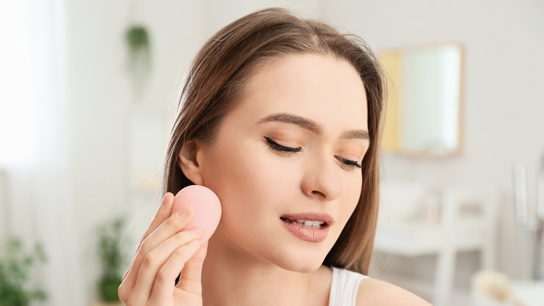 woman applying makeup on face 