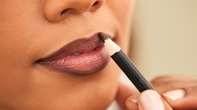 woman applying lipliner on lips 