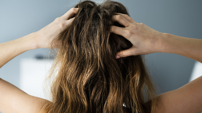 Woman scratching at her scalp.