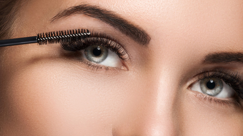 A woman applying mascara