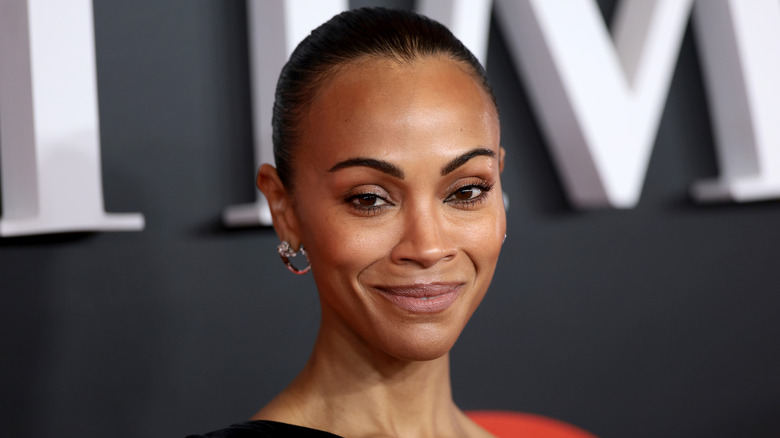 Zoe Saldana in a black gown with a slicked back bun.