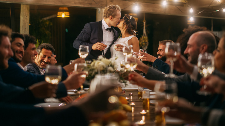 Bride, groom kissing over toast