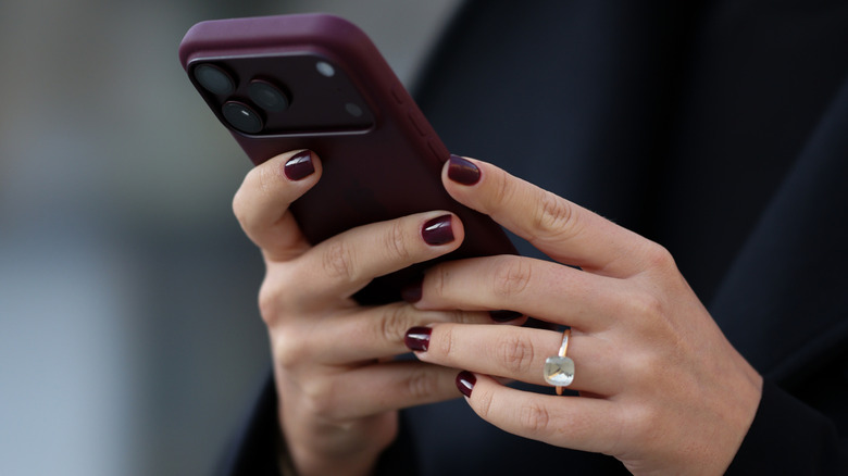 A woman with a Bordeaux manicure holding a phone