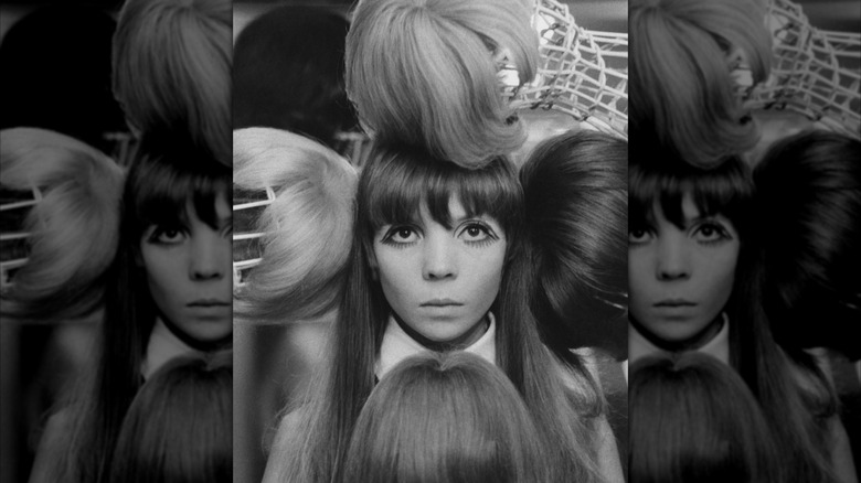 Model Penelope Tree during an editorial photoshoot surrounded by wigs in black and white