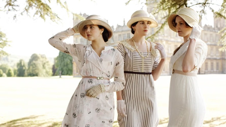 Lady Sybil, Lady Mary, and Lady Edith pictured wearing dresses and straw hats on Downton Abbey