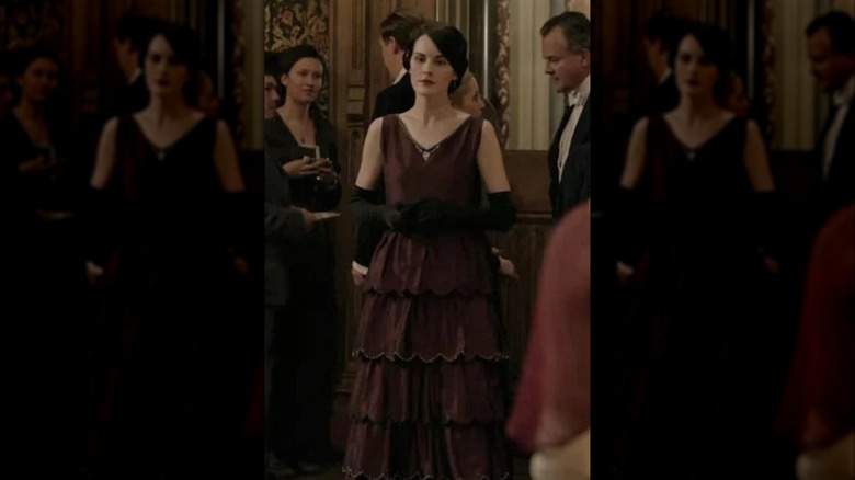 Michelle Dockery as Lady Mary wearing a burgundy strapless dress and long black gloves
