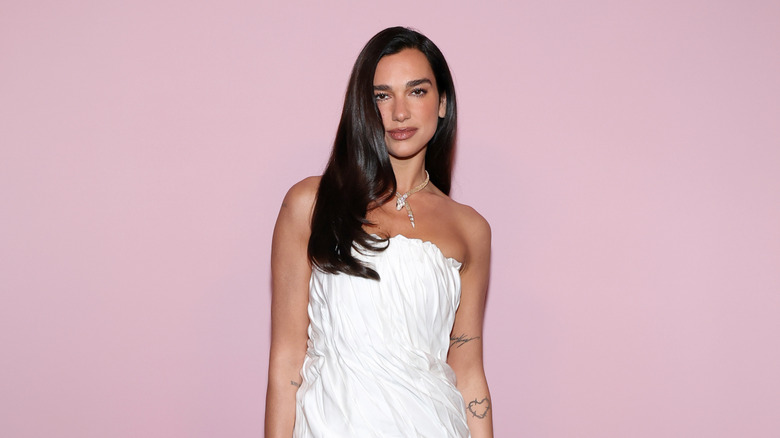 Dua Lipa smiles in a white gown