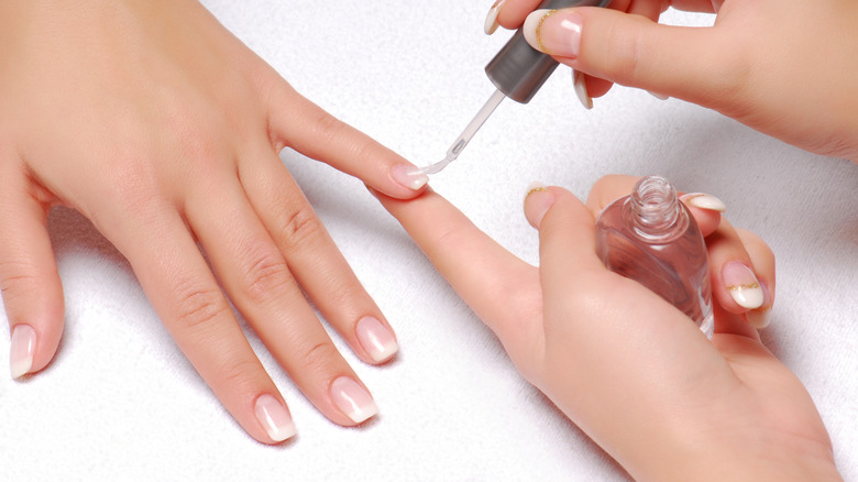 A person having their nails painted with clear polish