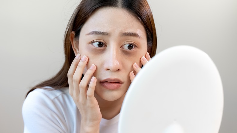 woman looking in the mirror at irritated face