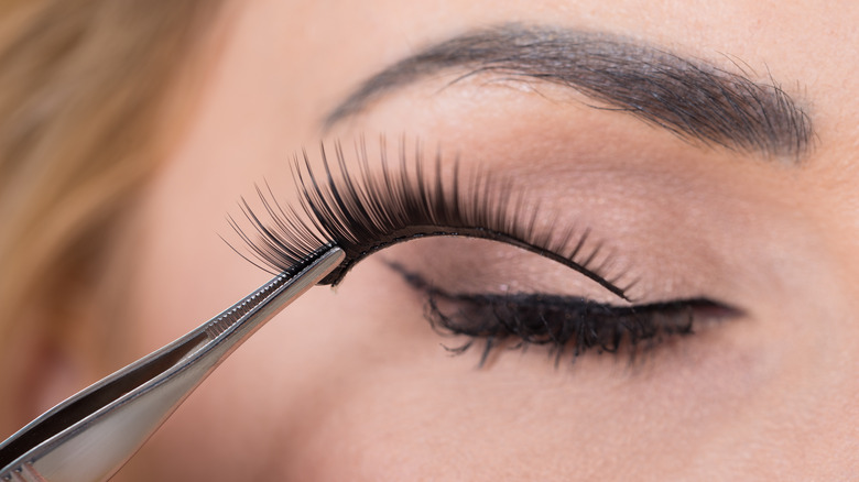 person putting on false lashes