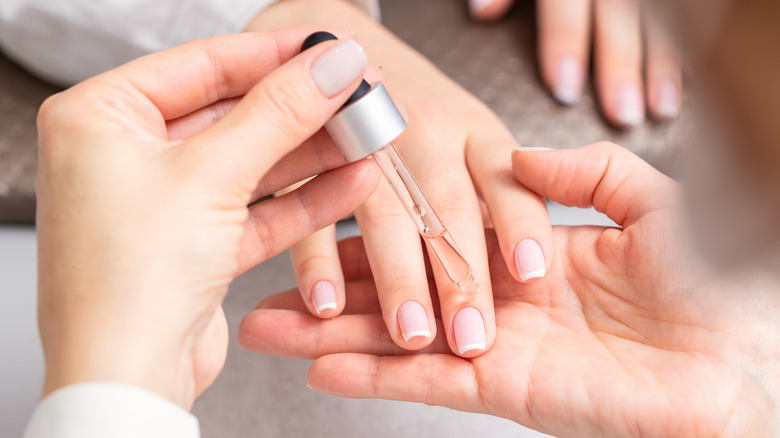 manicurist putting oil on nails