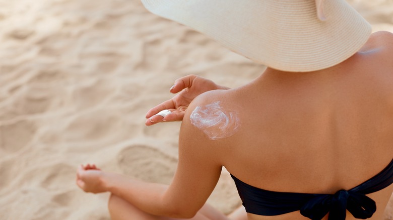 woman applying sunscreen to shoulder