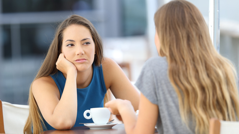 Annoyed woman listens to friend speak