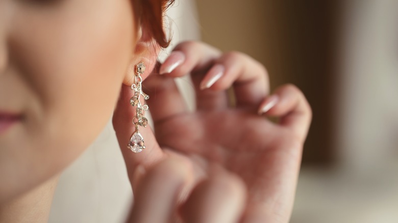 woman putting on earring