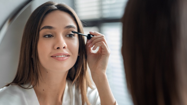 woman applying mascara in the mirror