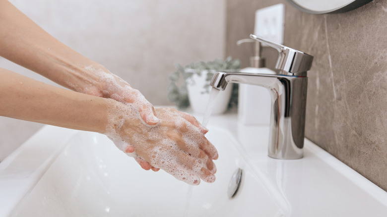 person washing hands at sink