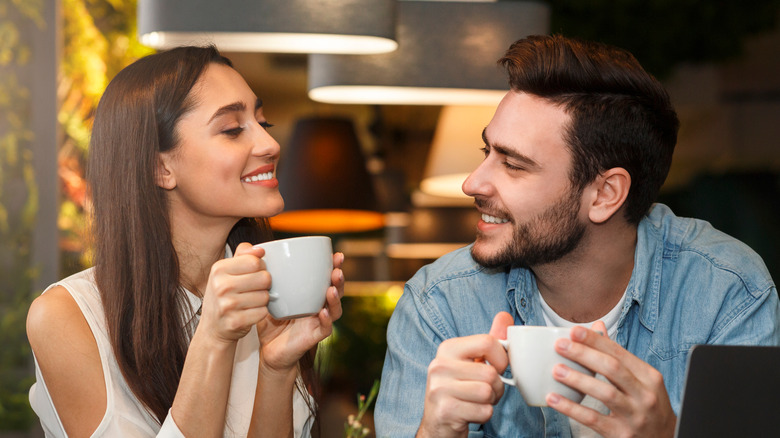 Couple looking at each other holding mugs