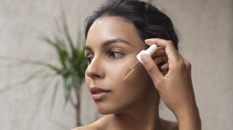 Woman applying oil to face