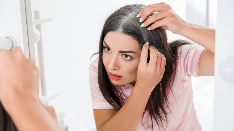 Woman examining gray roots in the mirror