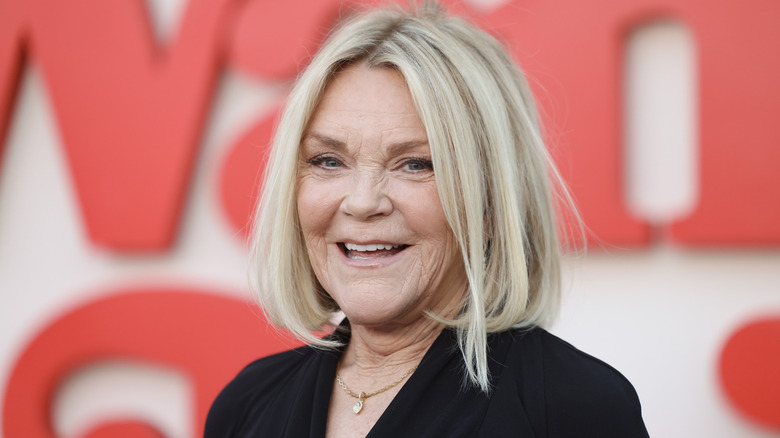 Actor Stephanie Faracy smiles in front of a blurred background at a red carpet event.