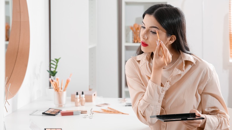 Woman applying eye makeup in bathroom