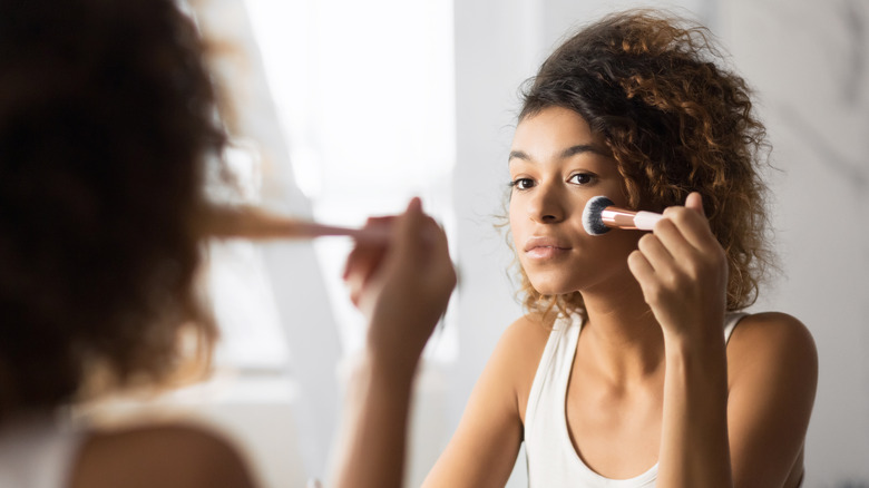 woman applying makeup to face 