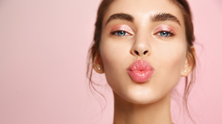 Woman kissy face pink background