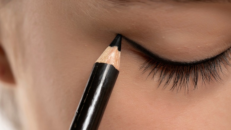woman using wooden black eyeliner