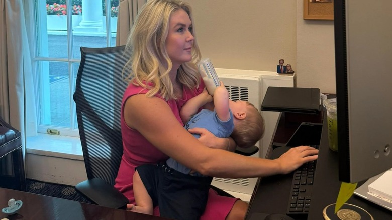 Karoline Leavitt holding her son while looking at a computer