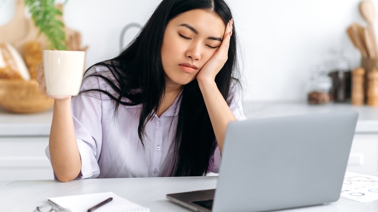 Girl closing eyes in front of laptop