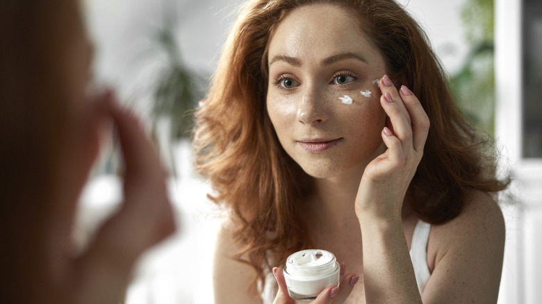 Woman applying skincare product to face