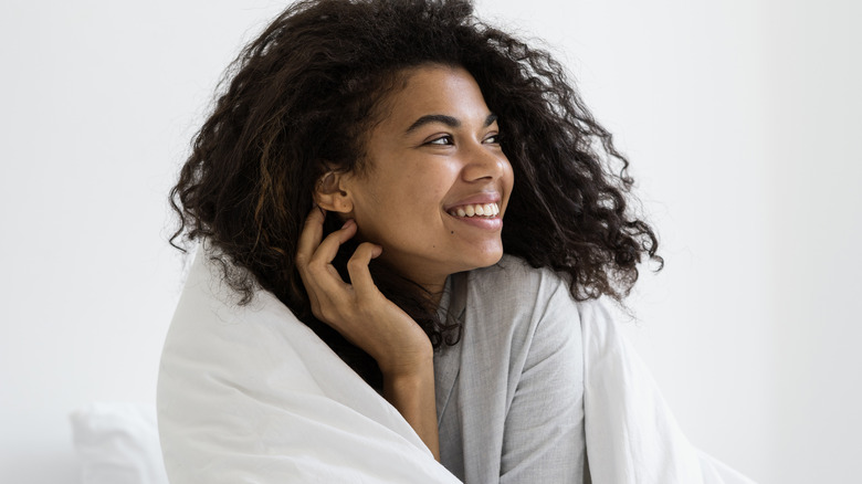 Happy Black woman wrapped in comforter