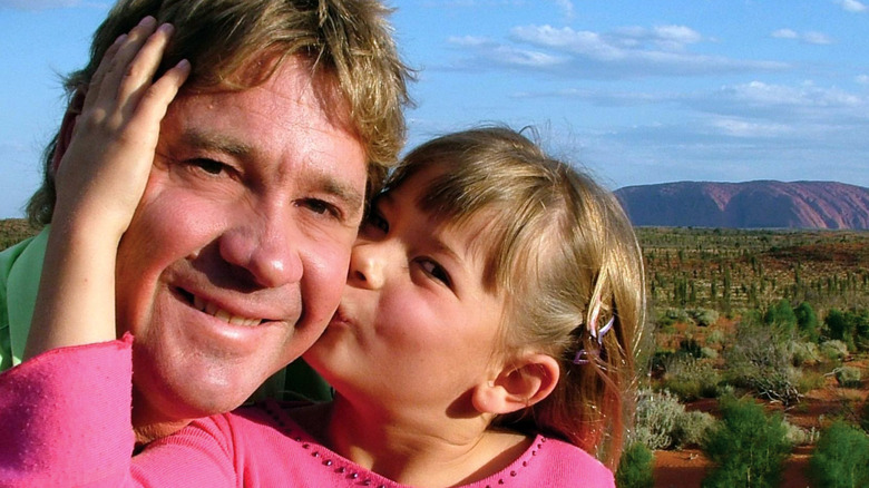 Young Bindi Irwin in a pink top kissing her father, Steve Irwin, on the cheek.